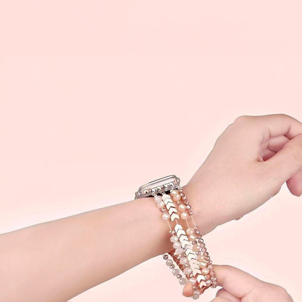 Bracelet de montre connectée en cristaux roses scintillants pour Apple Watch sur poignet féminin, fond rose pâle.