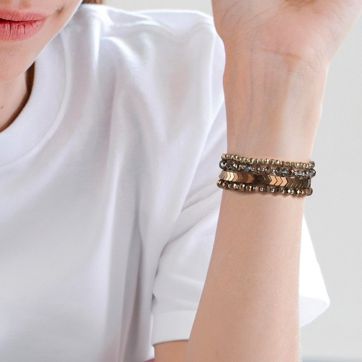 Bracelet de montre connectée en cristal effet perlé brun avec détails dorés, style multi-rangs élégant, porté au poignet.