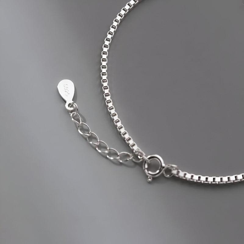 Bracelet en argent sterling avec chaîne fine à maillons carrés et fermoir anneau ressort.