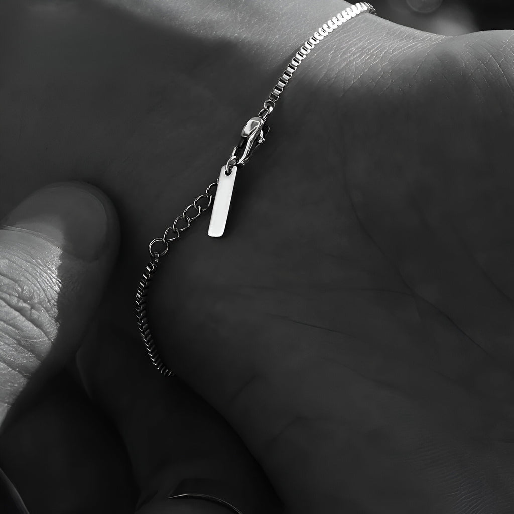 Bracelet homme fin en acier inoxydable argenté avec petite plaque rectangulaire et chaîne délicate.