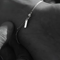 Bracelet homme fin en acier inoxydable argenté avec petite plaque rectangulaire et chaîne délicate.