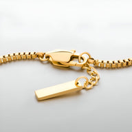 Bracelet homme en acier inoxydable doré, chaîne serpent avec fermoir mousqueton et pendentif rectangulaire lisse.