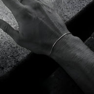 Bracelet fin en acier inoxydable argenté, design minimaliste, porté au poignet homme.