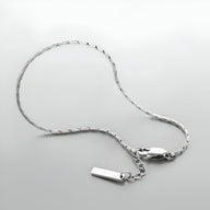 Bracelet homme en acier inoxydable argenté, chaîne fine avec petit pendentif rectangulaire lisse.