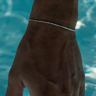 Bracelet fin en acier inoxydable argenté, style minimaliste, porté au poignet masculin.