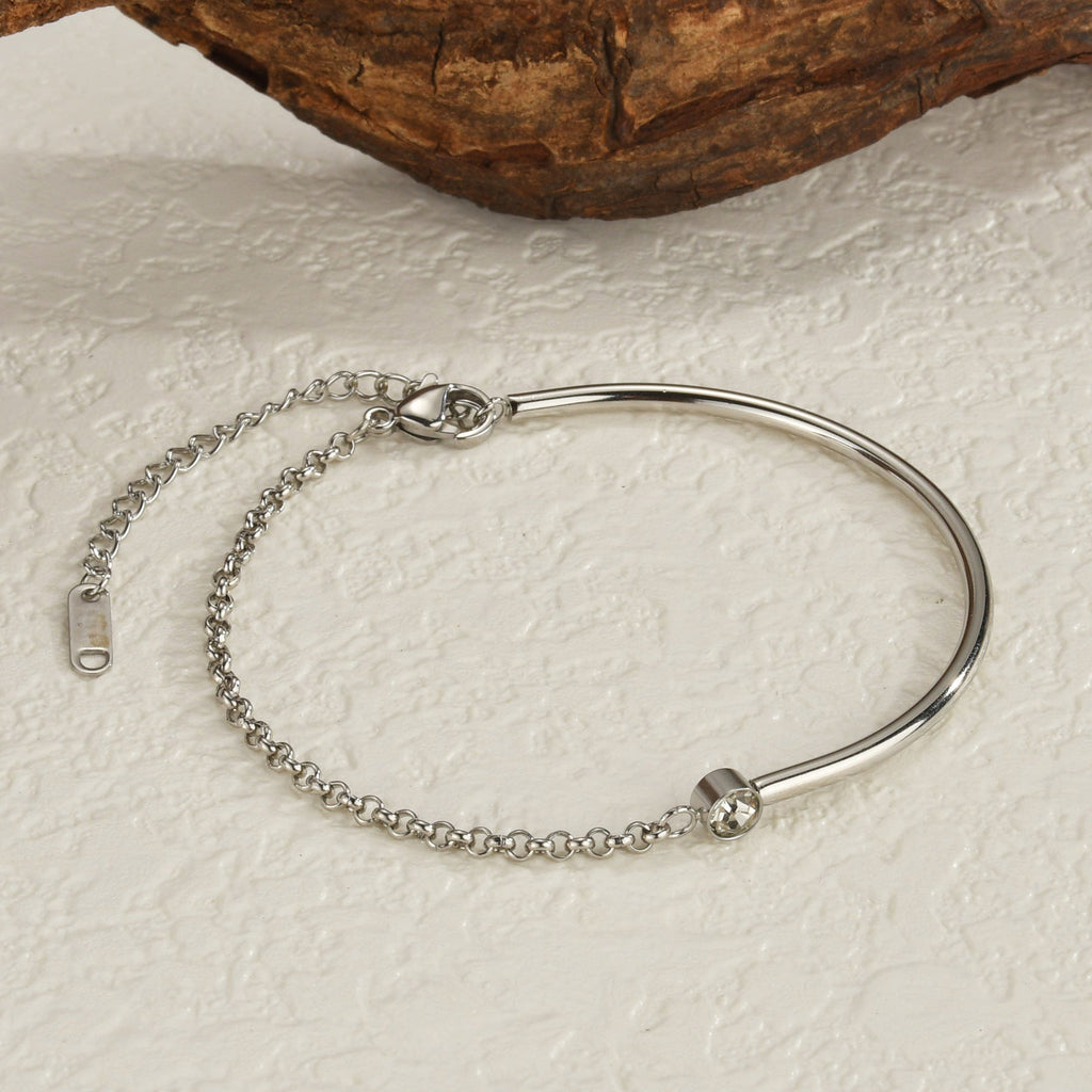 Bracelet fin en titane argenté avec une pierre de zirconium ronde et chaîne ajustable.