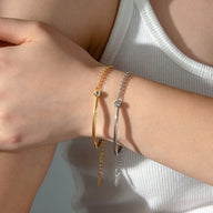 Bracelet en titane or avec pierre de zirconium et bracelet argenté fin, style minimaliste.