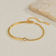 Bracelet fin en titane doré avec chaine délicate et pierre de zirconium scintillante.