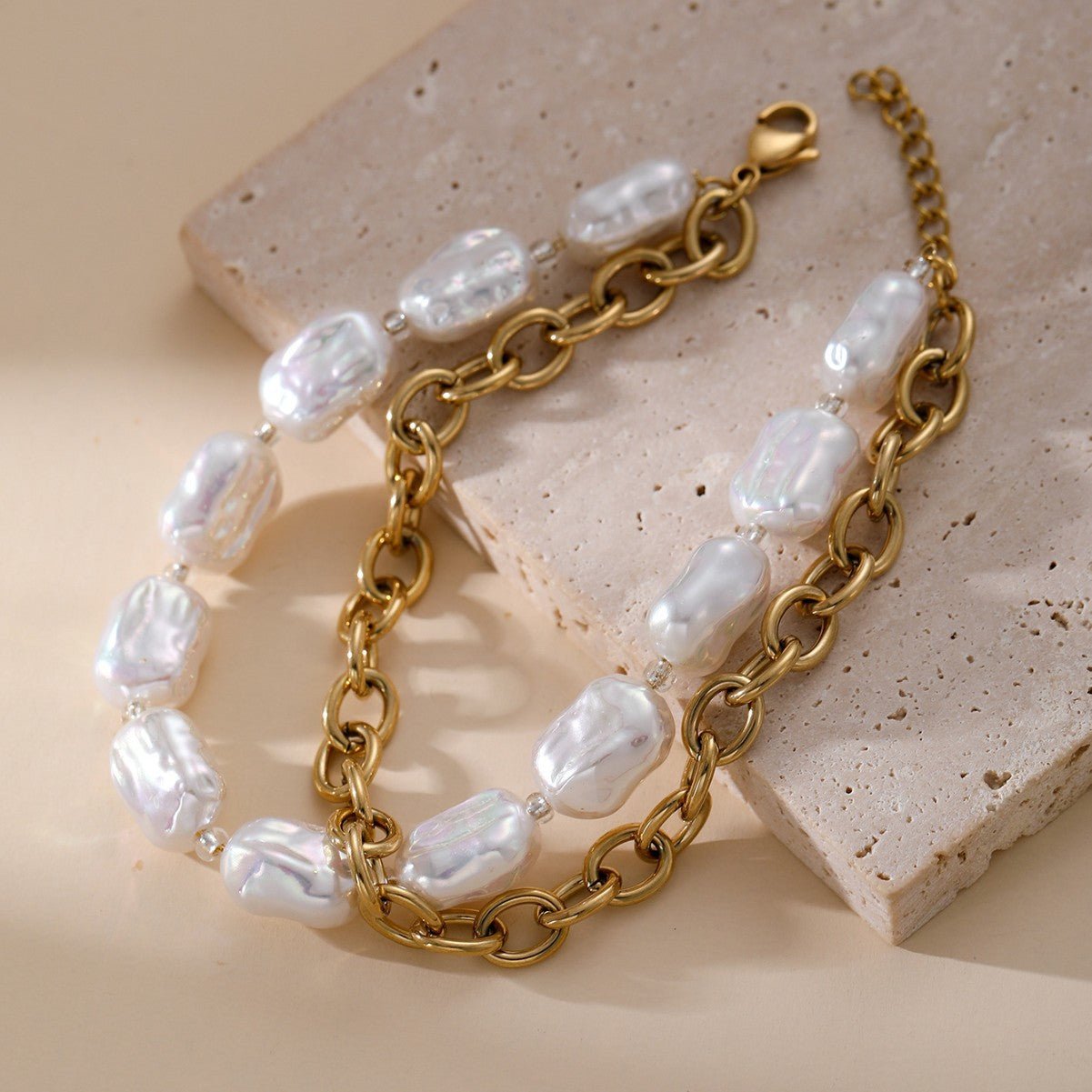 Bracelet double rang doré en acier inoxydable avec perles blanches irrégulières et maillons ovales larges.