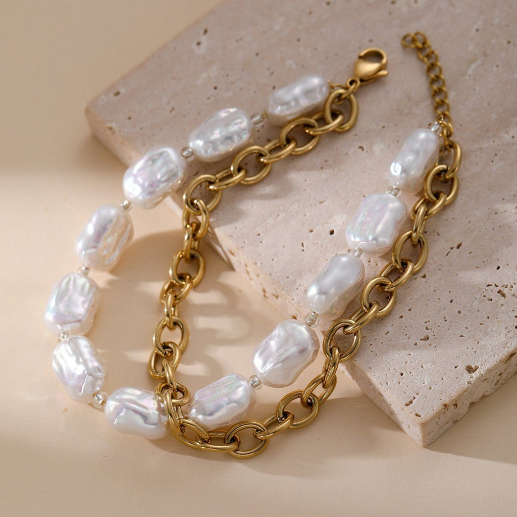 Bracelet double rang doré en acier inoxydable avec perles blanches irrégulières et maillons ovales larges.