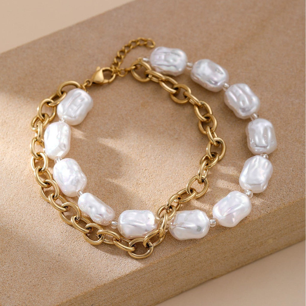Bracelet double rang doré en acier inoxydable avec perles blanches irrégulières et maillons larges.