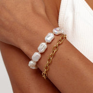 Bracelet double rang doré en acier inoxydable avec perles blanches irrégulières et maillons ovales larges.