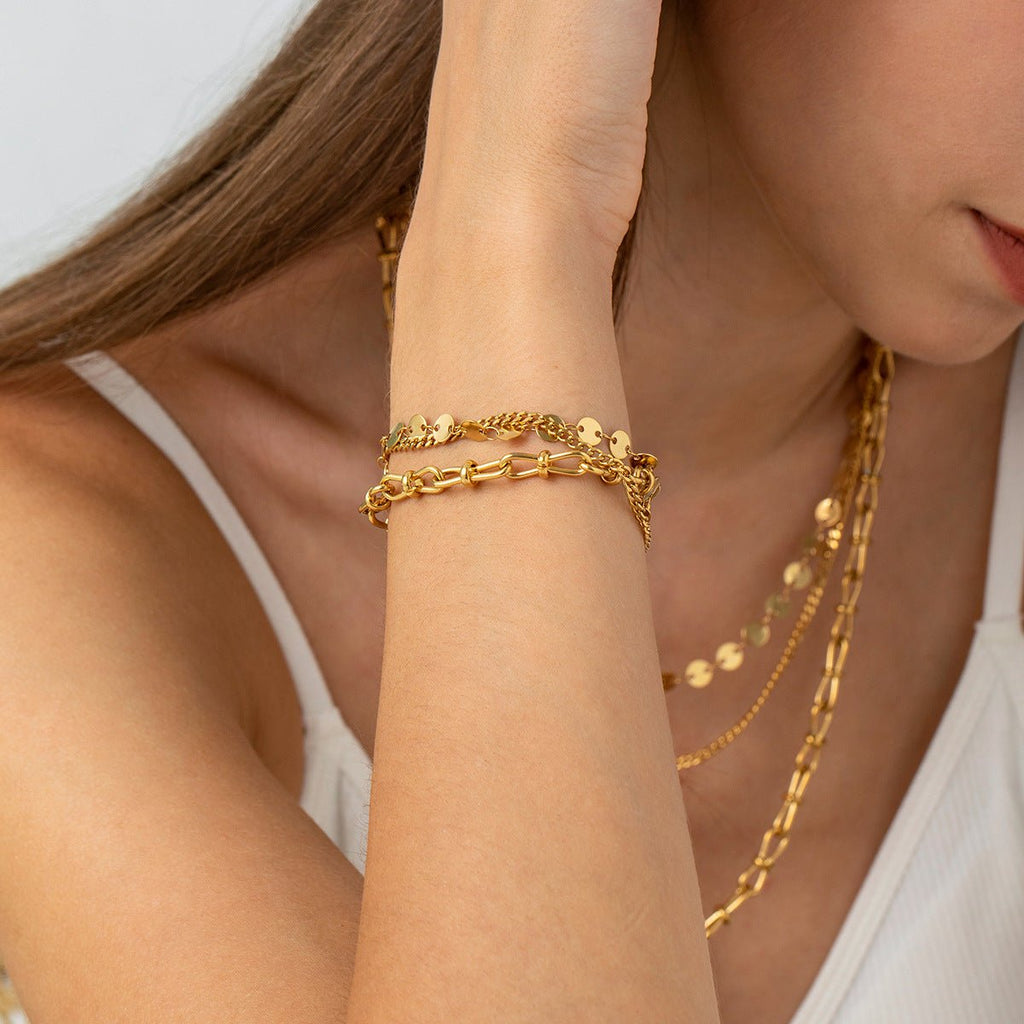 Bracelet en acier inoxydable doré avec chaînes multiples et disques ronds brillants, porté au poignet féminin.