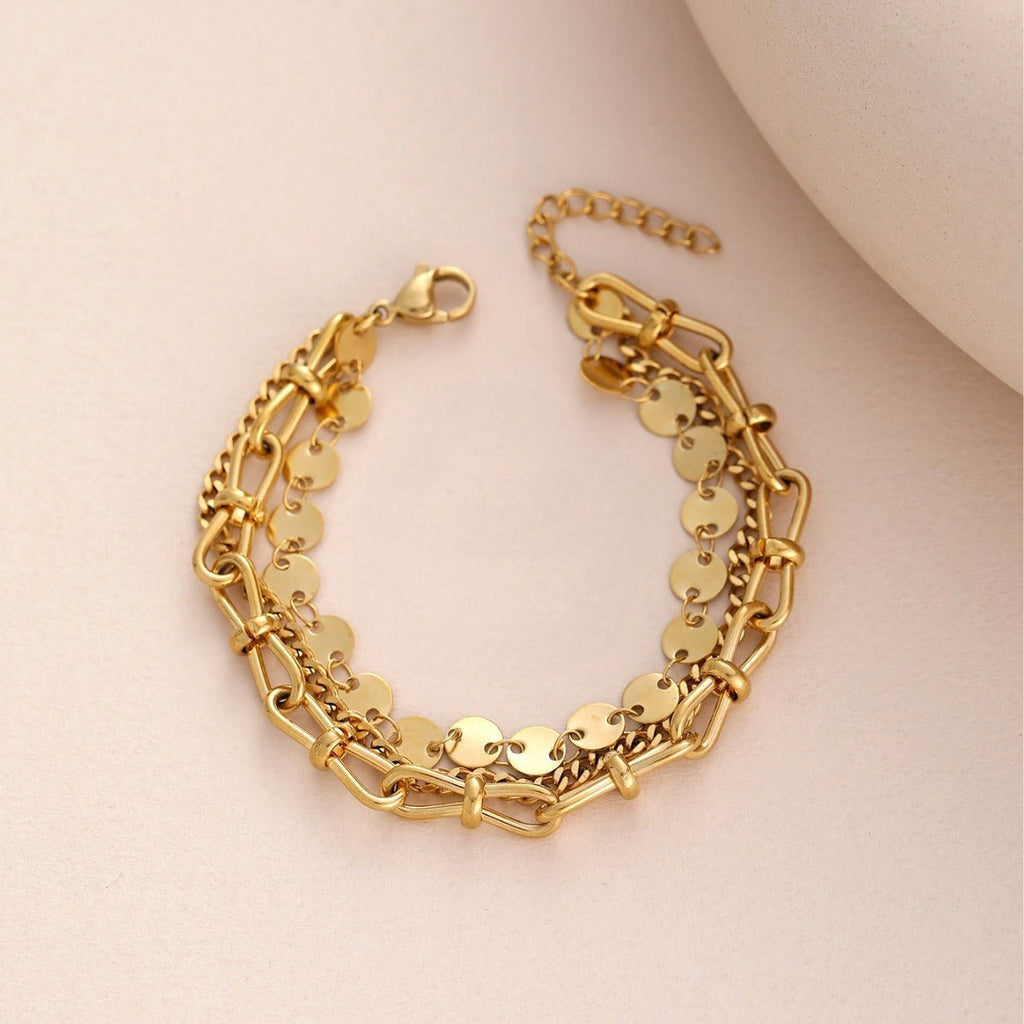 Bracelet doré en acier inoxydable avec disques ronds et deux rangées de mailles épaisses, fermoir mousqueton ajustable.