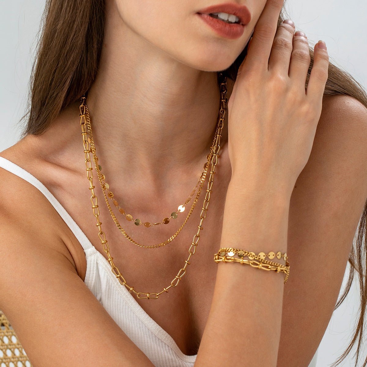 Bracelet doré en acier inoxydable avec disques ronds et maillons multiples porté au poignet Femme.
