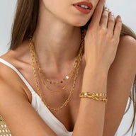 Bracelet doré en acier inoxydable avec disques ronds et maillons multiples porté au poignet Femme.