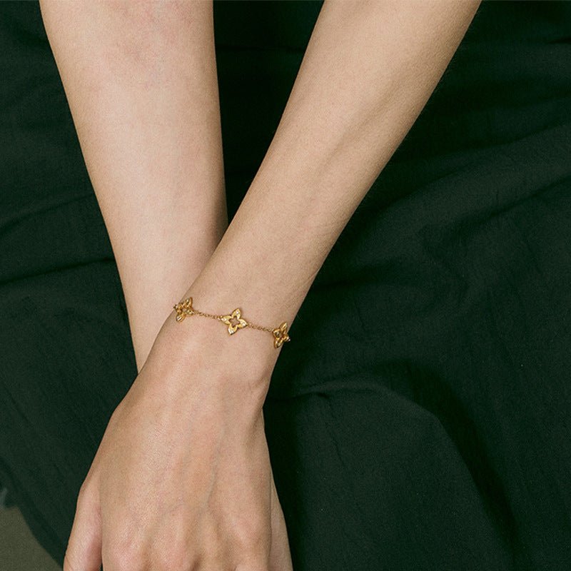 Bracelet doré en titane avec motif trèfle ajouré et éclat de zircon, chaîne fine plaquée or élégante.