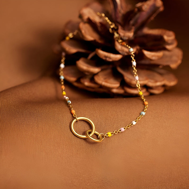 Bracelet en argent sterling avec deux anneaux entrelacés et chaîne délicate dorée.