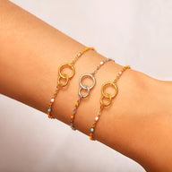 Trois bracelets fins avec double anneaux, en argent sterling et or, ornés de petites perles colorées.