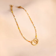Bracelet doré pour femme avec deux anneaux entrelacés et chaîne délicate à maillons fins.