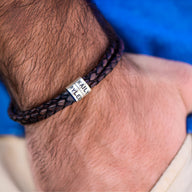 Bracelet double cordon cuir tressé noir avec plaques métalliques arrondies gravées, style masculin.