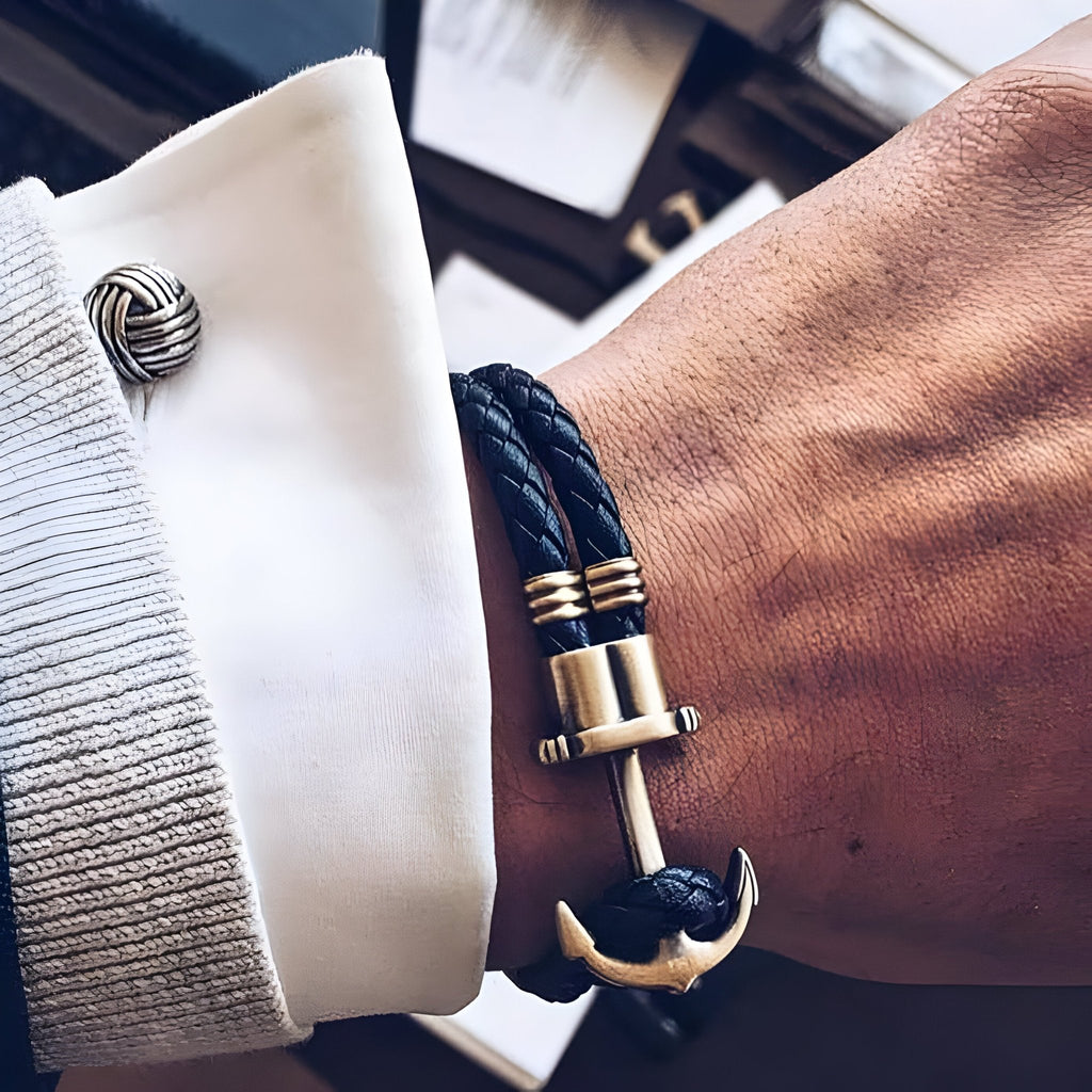 Bracelet double cordon noir tressé avec motif ancre antique dorée sur poignet.