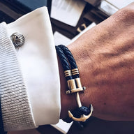 Bracelet double cordon noir tressé avec motif ancre antique dorée sur poignet.