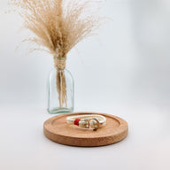 Bracelet double cordon beige avec motif ancre large dorée et détail rouge, style marin élégant.