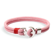 Bracelet double cordon rose clair avec motif ancre large en métal argenté et nœud rouge vif.