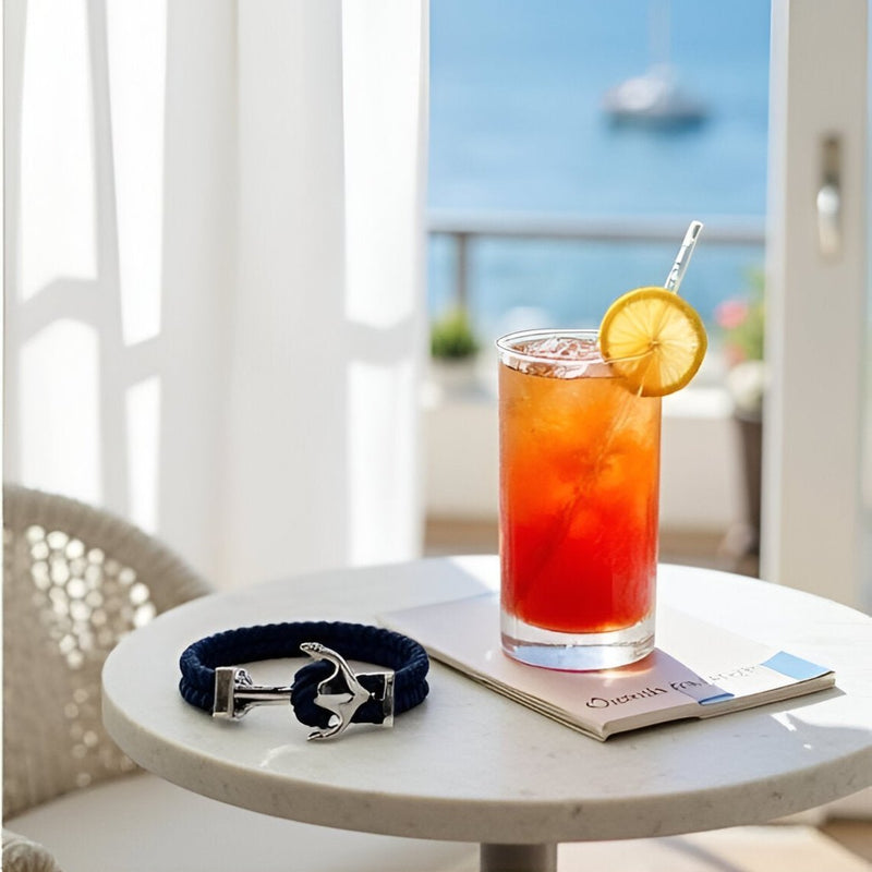 Bracelet double cordon bleu marine avec motif ancre argentée posé sur une table ronde en marbre blanc.