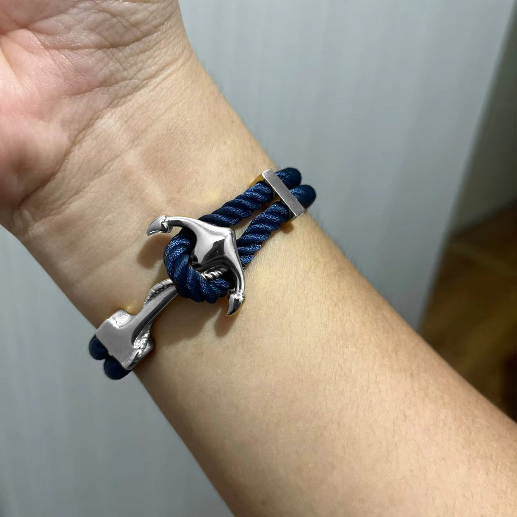 Bracelet double cordon bleu marine avec motif ancre en métal argenté sur poignet.