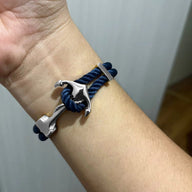 Bracelet double cordon bleu marine avec motif ancre en métal argenté sur poignet.