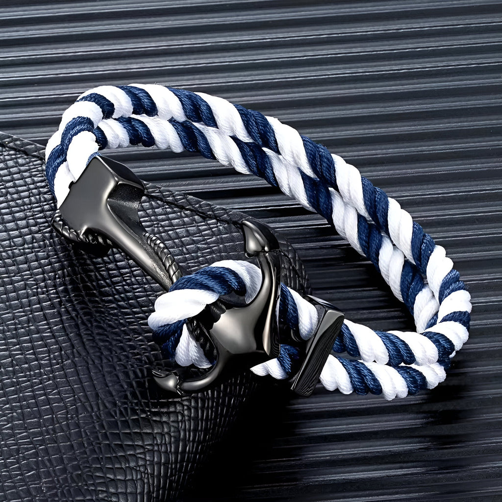 Bracelet double cordon bleu et blanc avec motif ancre noire en métal brillant.
