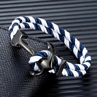 Bracelet double cordon bleu et blanc avec motif ancre noire en métal brillant.