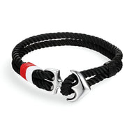 Bracelet double cordons noirs avec ancre marine argentée et détail rouge et blanc.