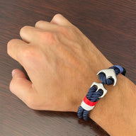 Bracelet double cordons bleu blanc rouge avec ancre marine en métal argenté sur poignet homme.