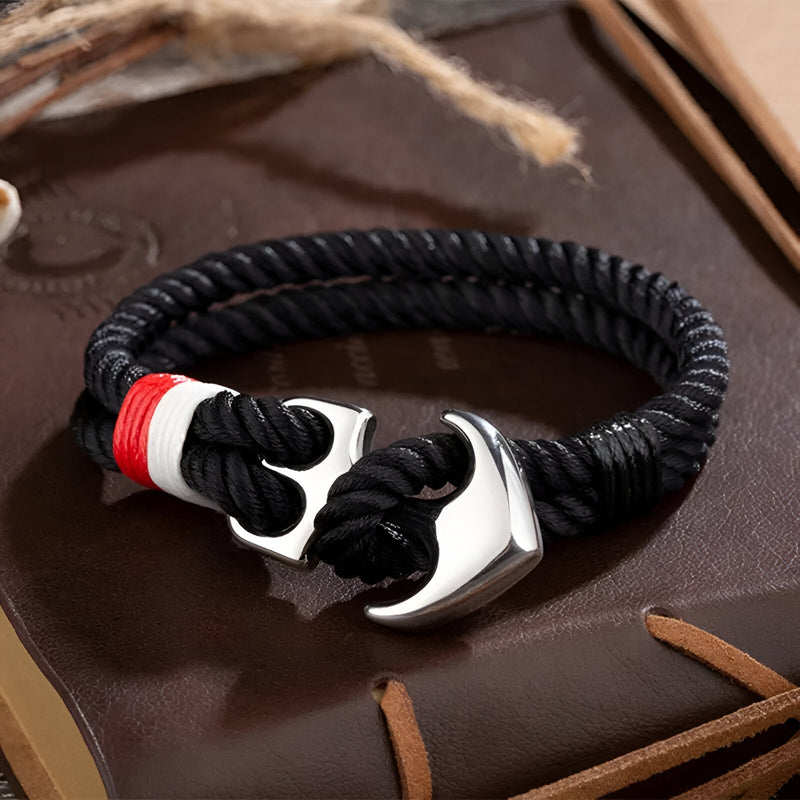 Bracelet double cordons noirs avec ancre marine argentée et détail tricolore rouge blanc bleu.