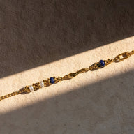 Bracelet double en acier inoxydable doré avec perles en lapis lazuli bleu profond et détails tordus élégants.