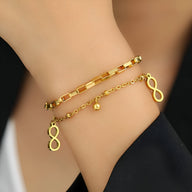 Bracelet double fin en acier inoxydable doré avec charms infini et petites perles élégantes.