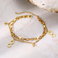 Bracelet double en acier inoxydable doré avec chaînes fines et charms infini délicats.