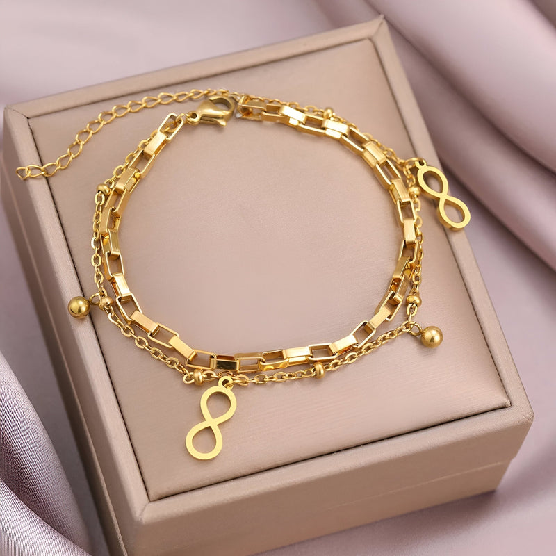 Bracelet double en acier inoxydable doré avec charms infini et petites perles fines.