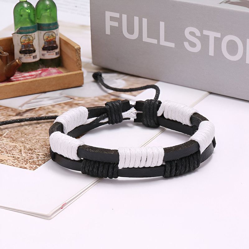 Bracelet double en cuir noir et blanc avec détails cirés et fermoir coulissant en macramé noir.