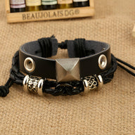 Bracelet double noir en cuir avec détails métalliques argentés et tissage en corde noire ajustable.