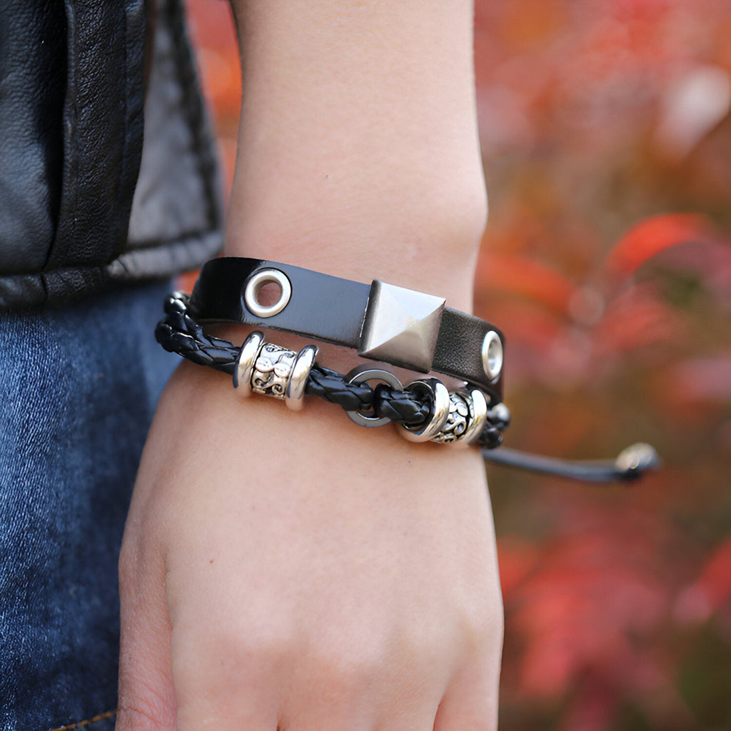 Bracelet double en cuir noir avec détails métallisés argentés, design mixte et tressé.