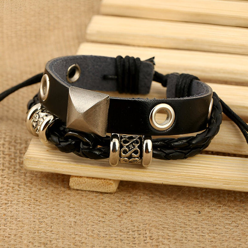 Bracelet double noir en cuir avec détails métallisés argentés et tresse décorative.