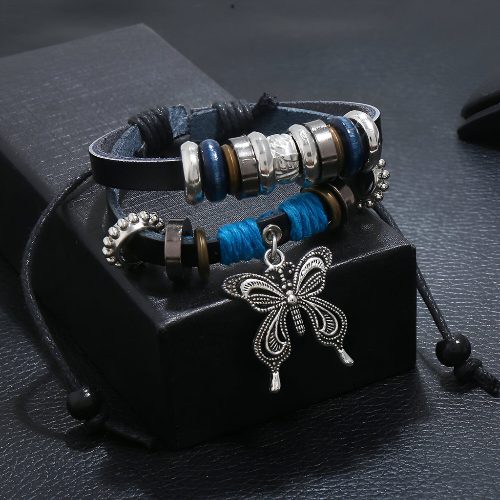 Bracelet double en cuir bleu avec perles argentées et charm papillon détaillé en métal.