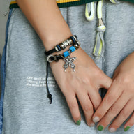 Bracelet double en cuir bleu avec charm papillon argenté et perles décoratives pour femme.