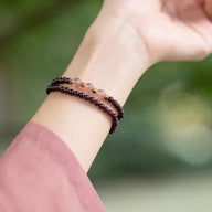 Bracelet double en perles de grenat rouge et quartz rose sur poignet féminin, style délicat et élégant.