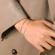 Bracelet double rang fin en titane plaqué or, design minimaliste élégant sur peau claire.