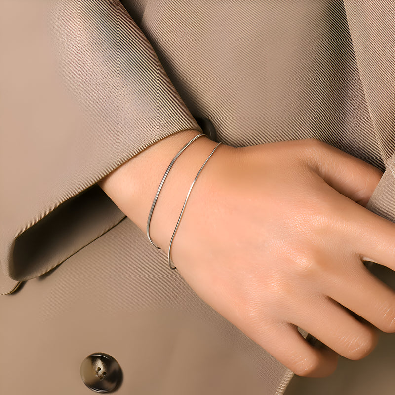 Bracelet double rang fin en titane plaqué or, design minimaliste élégant sur peau claire.